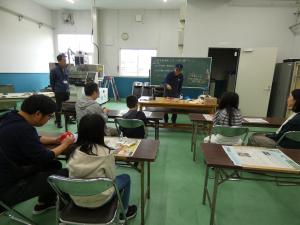 指導員の説明を聞く参加者の全体写真