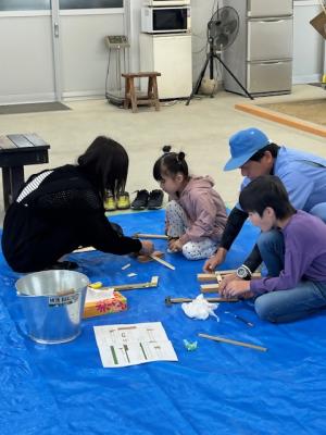 指導員と一緒にゴム鉄砲を作っている写真