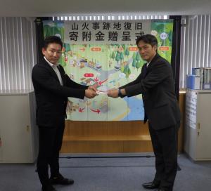 楢村会長から中川農林水産部長へ目録を渡している様子