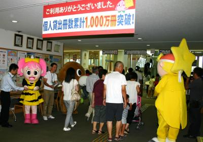 県立図書館の個人貸出冊数1000万冊突破を祝して来館者を職員が出迎える写真